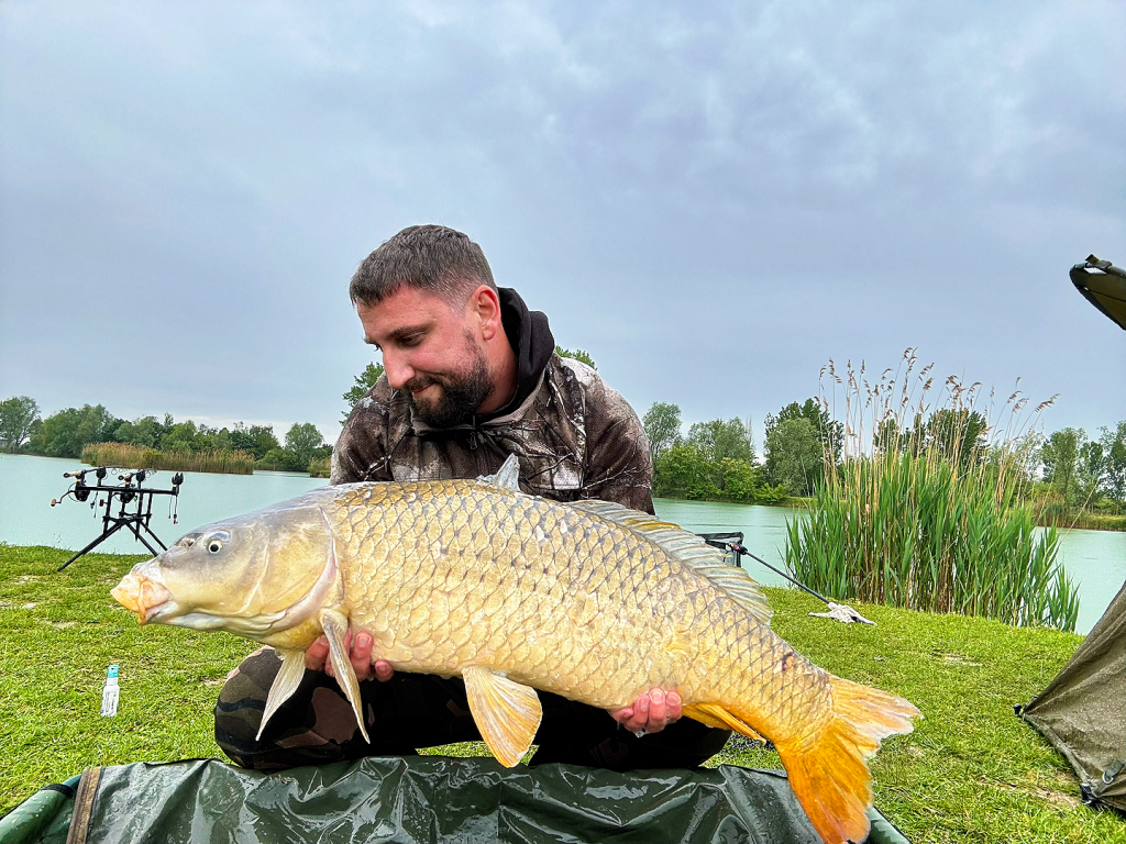 Dejan from FishingChief holding a common carp by a Croatian lake