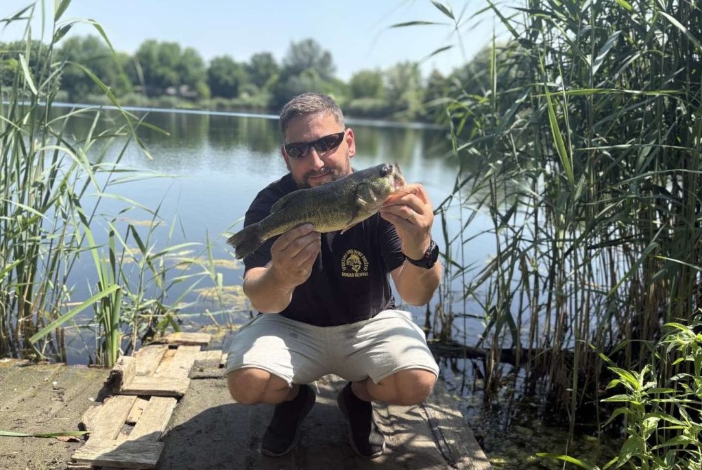 Bass fishing from shore with a largemouth bass caught beside a freshwater lake
