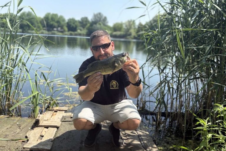 Bass fishing from shore with a largemouth bass caught beside a freshwater lake