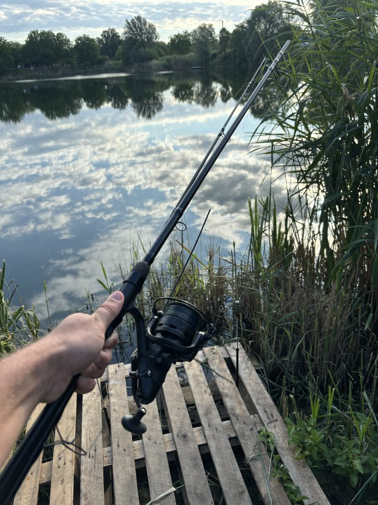 Carp fishing rod and spinning reel being used beside a lake